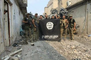 Soldados iraquíes con una bandera capturada del EI