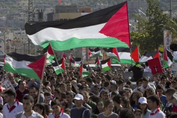 Arab Israelis wave Palestinian flags during a rally commemorating  Land Day on March 30, 2014 in the northern Arab-Israeli town of Arrabe. The annual Land Day demonstrations are held to remember six Arab Israeli protesters who were shot dead by Israeli police and troops during mass demonstrations in 1976 against plans to confiscate Arab land in the Galilee. AFP PHOTO/AHMAD GHARABLI